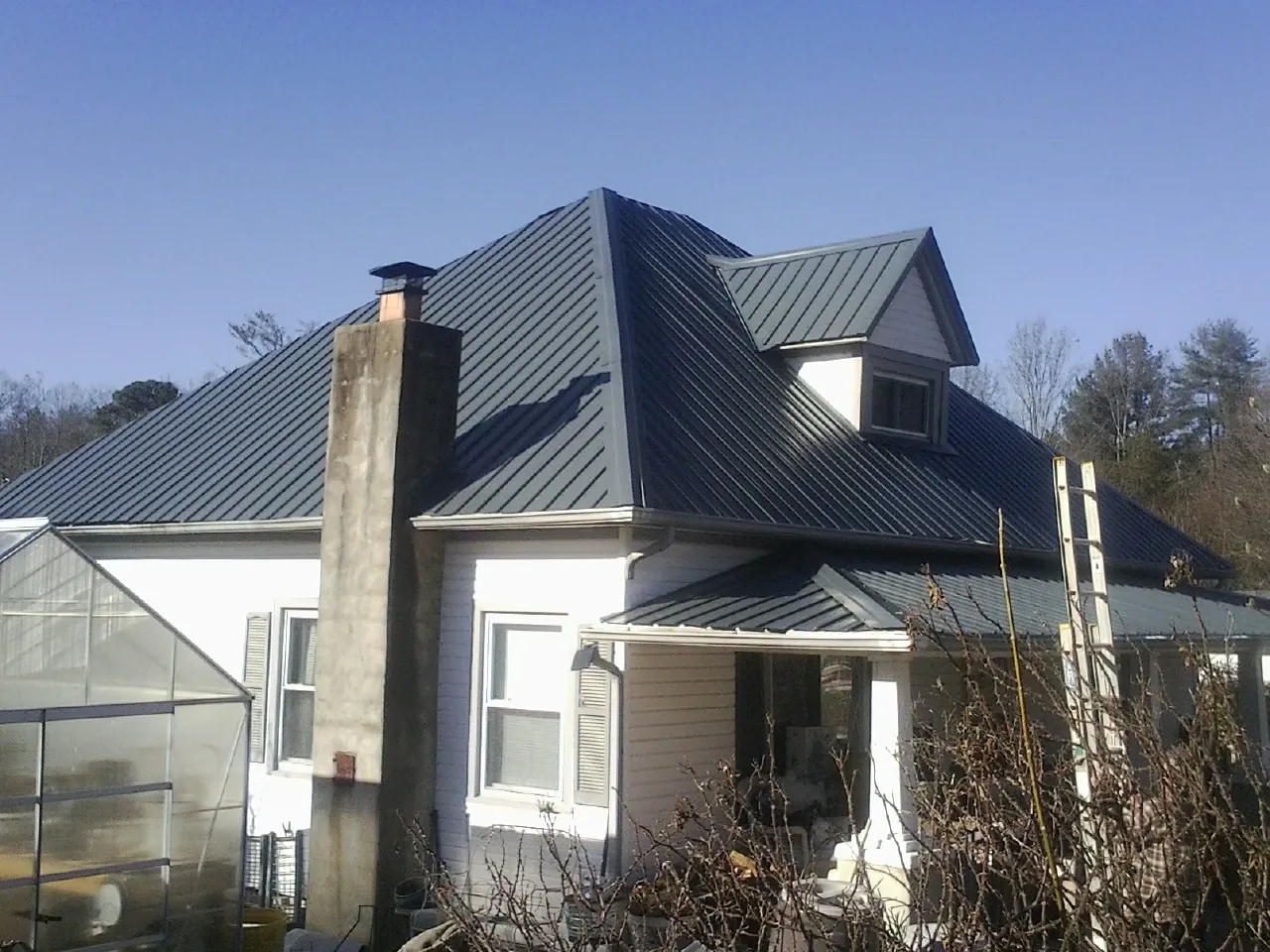Dark blue standing seam metal roof on a white farmhouse with dormer — Slate & Tile Roof Repair by Roofing Brothers in Fairbury