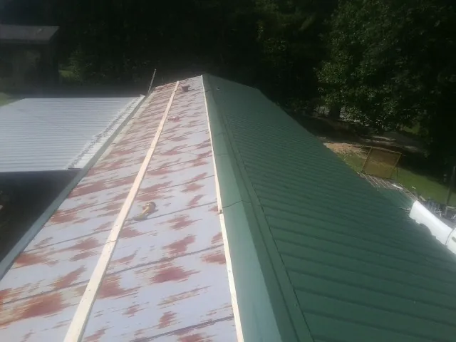 Old rusted panels beside newly installed green metal roofing — Wind Damage Roof Repair by Roofing Brothers in Fairbury