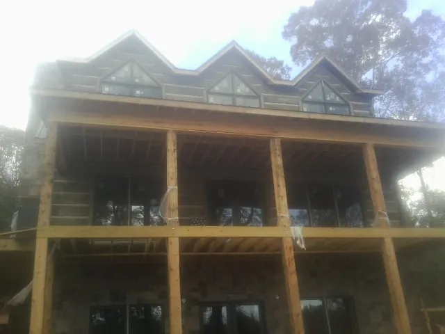 Dormers and porch framing on a large log home under construction — Roof Coating work by our crew in Fairbury