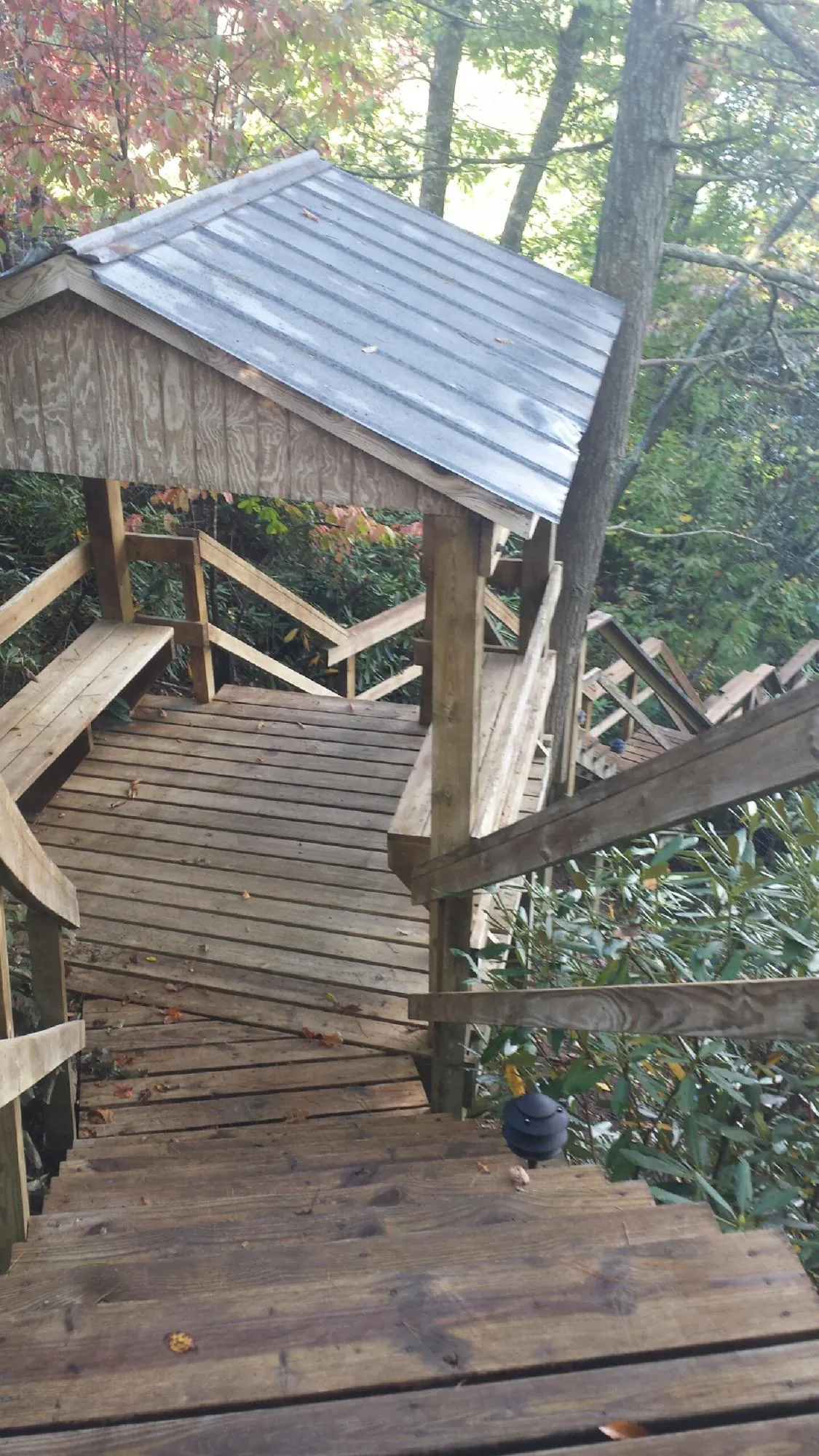 Metal roofed shelter over wooden steps on a wooded walkway — Skylight Repair & Installation work by our crew in Fairbury