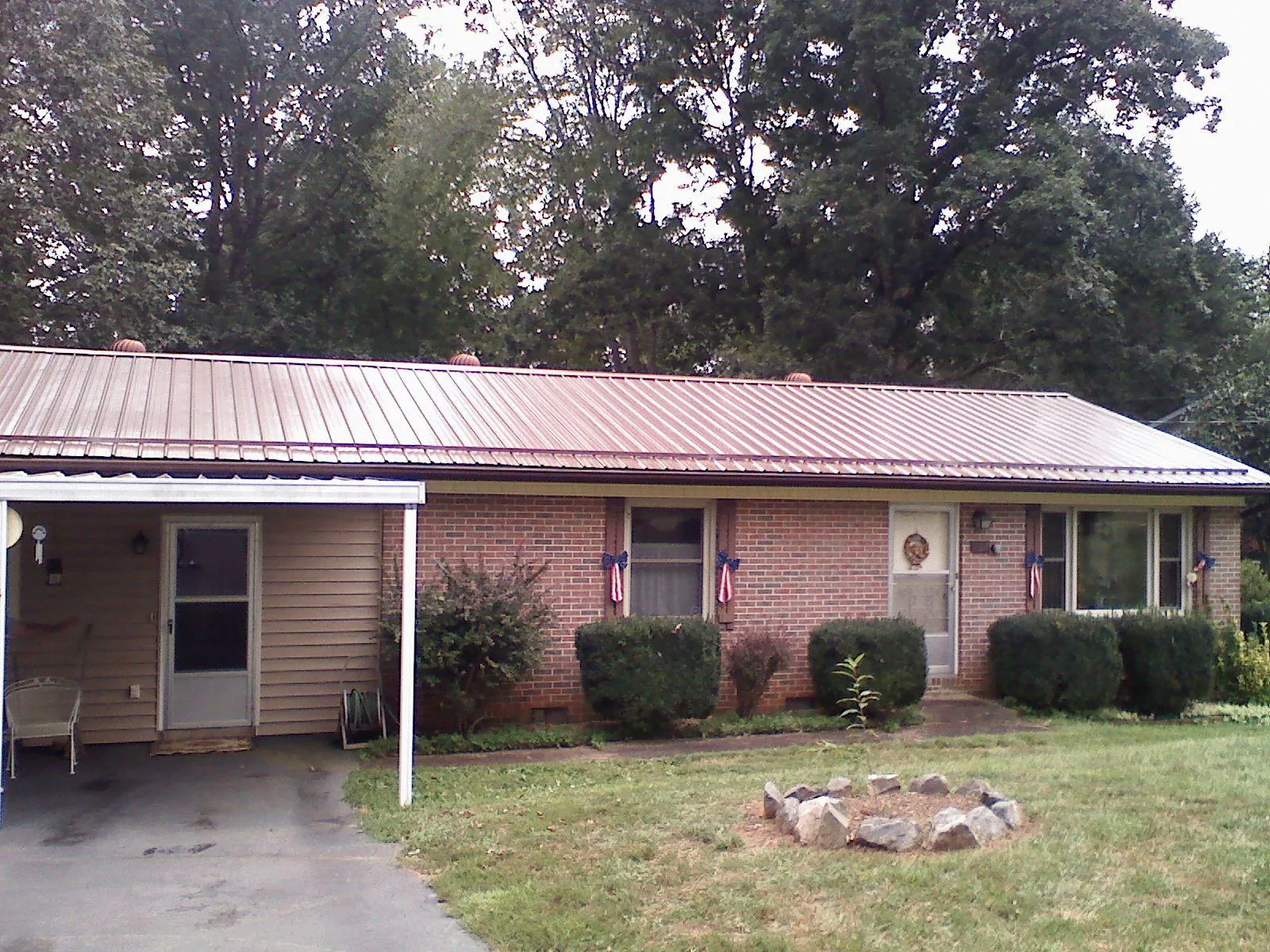 Bronze metal roof and carport on a brick ranch home — Roof Repair work by our crew in Fairbury