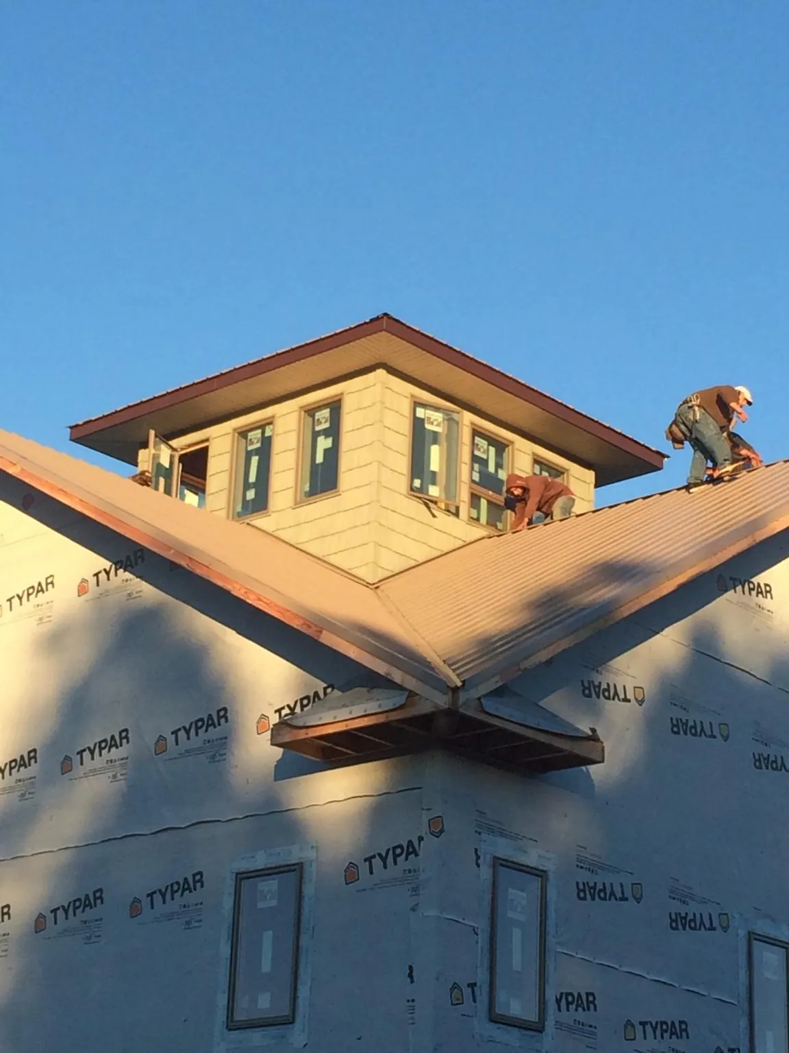 Roofers working around a rooftop cupola on a new metal roof at sunset — Roof Waterproofing in Fairbury by Roofing Brothers